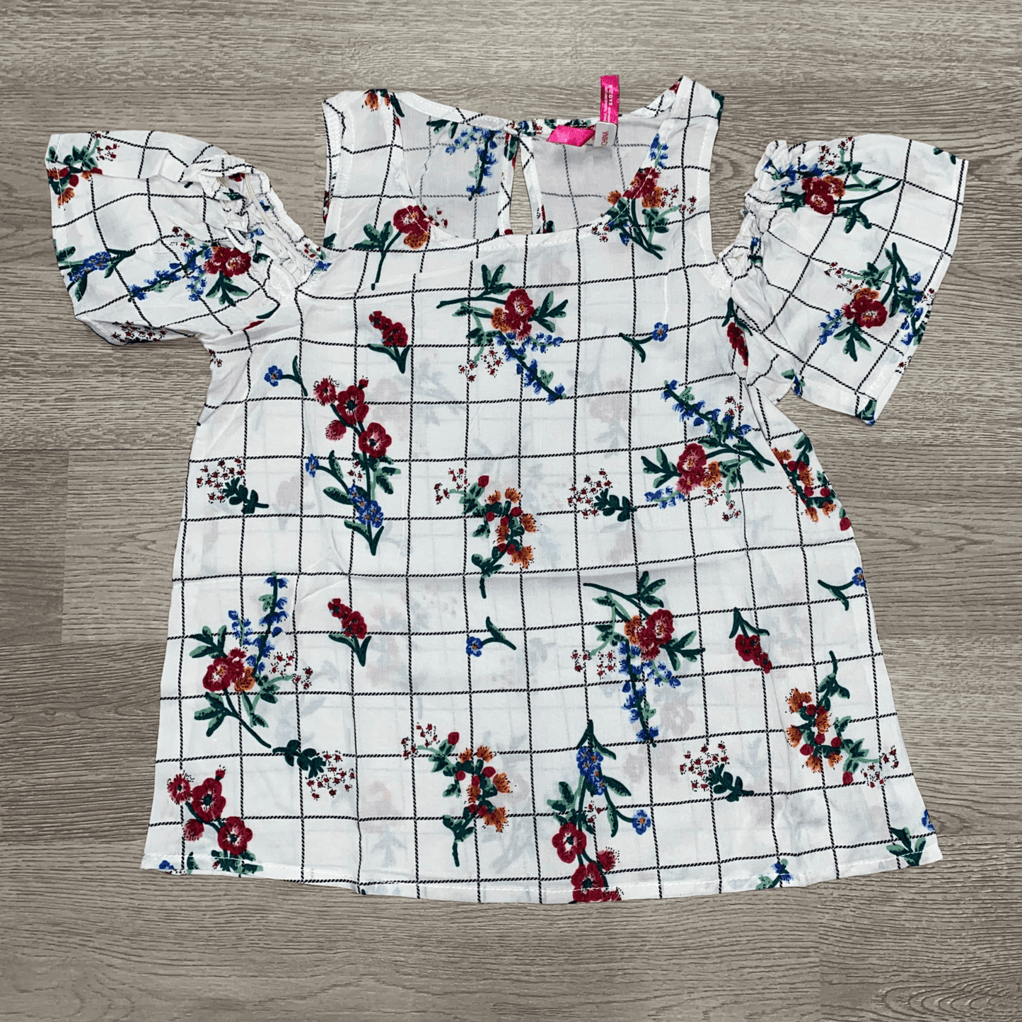 You little one will be ready for a day of fun and learning at school in this white cold shoulder fashion top. This top features ruffle sleeves and a plaid floral print.