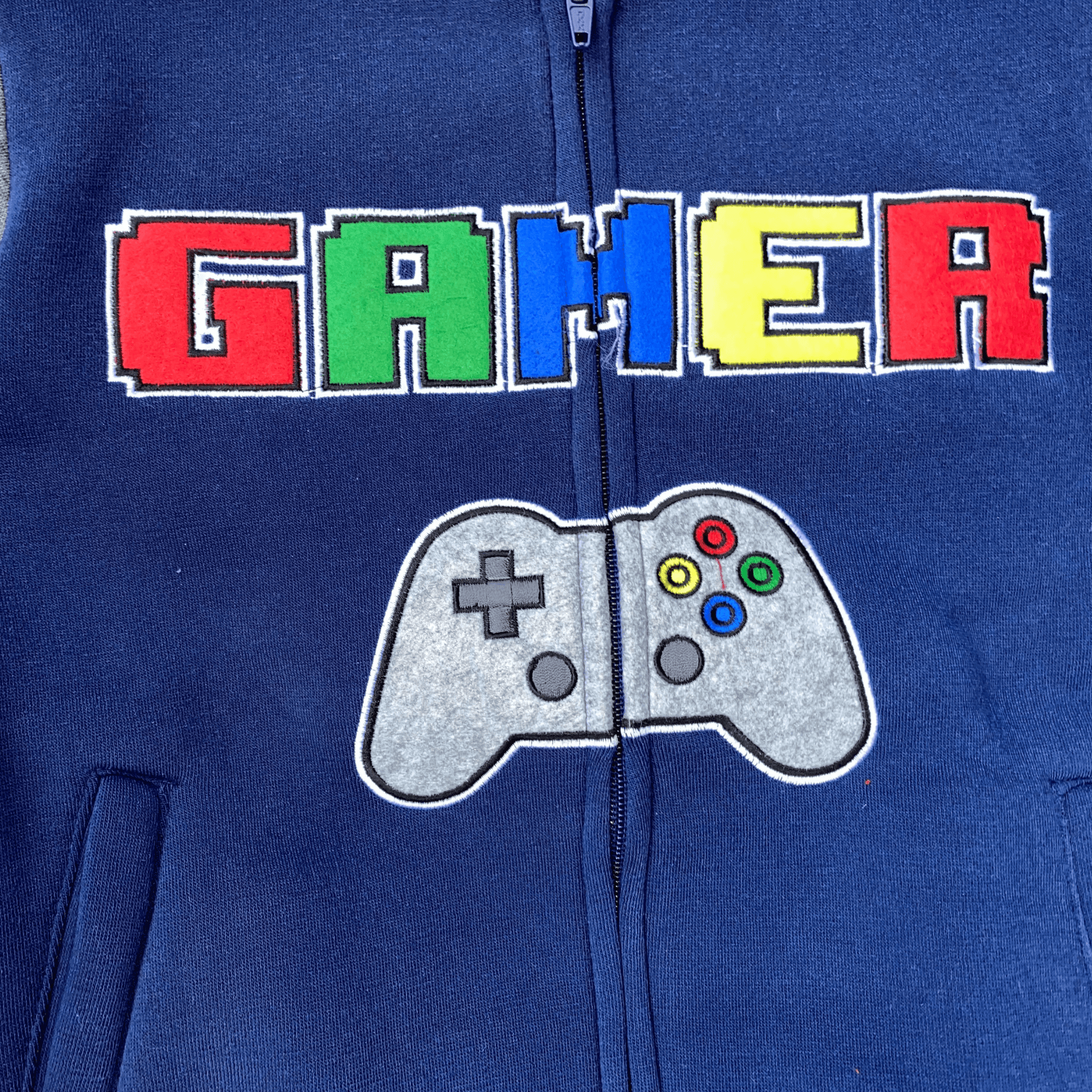 Fun gamer fleece set with hoodie. This colorful and fun set features "Gamer" and a picture of a controller embroidered on the front. It also has embroidered arms with "Push" and "Start". This is a great set for all of the little gamers out there.  This set features a zipper front hoodie and elastic around the ankles.