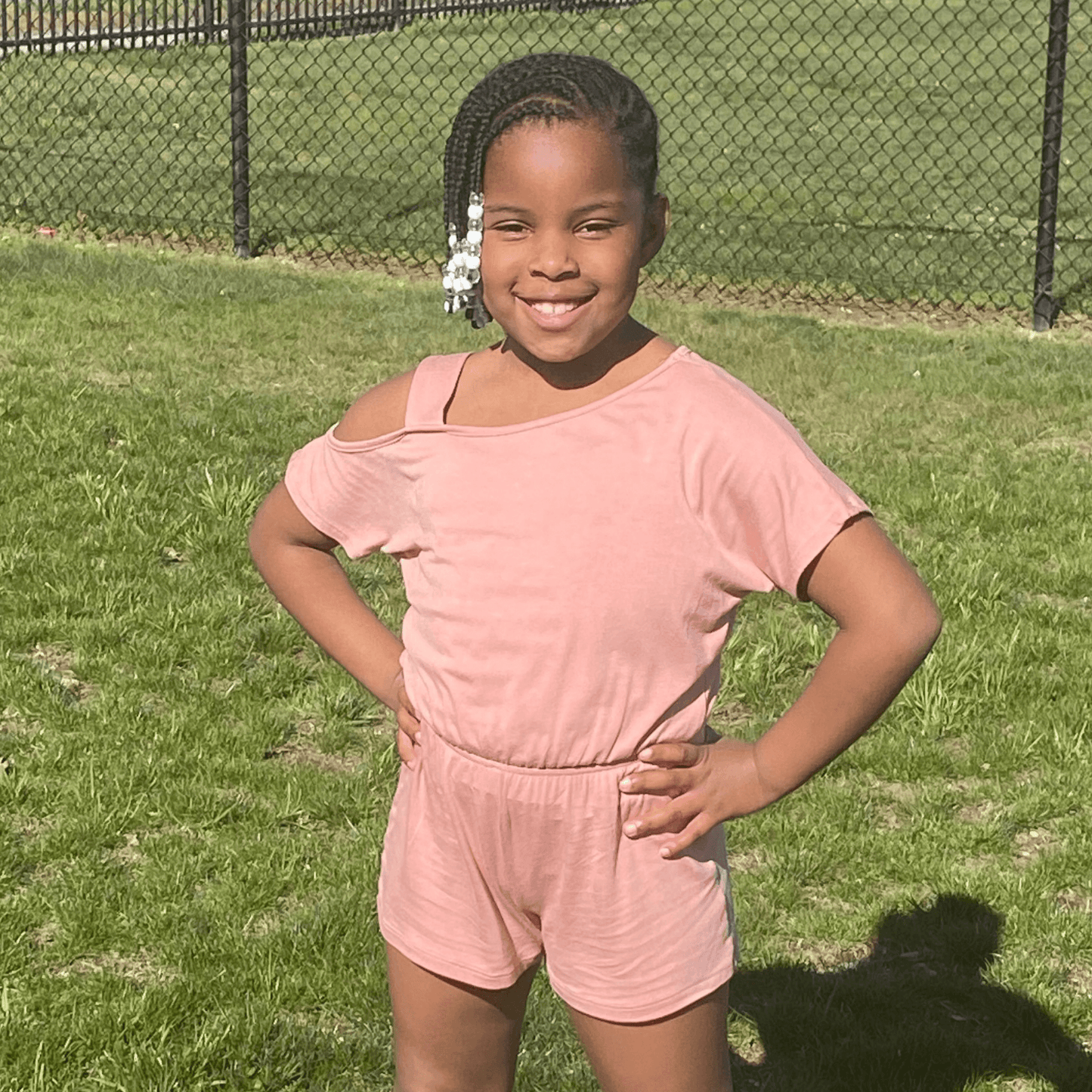 This short sleeve pink romper features cold shoulder detailing on one shoulder and an elasticized waist which allows for plenty of movement.