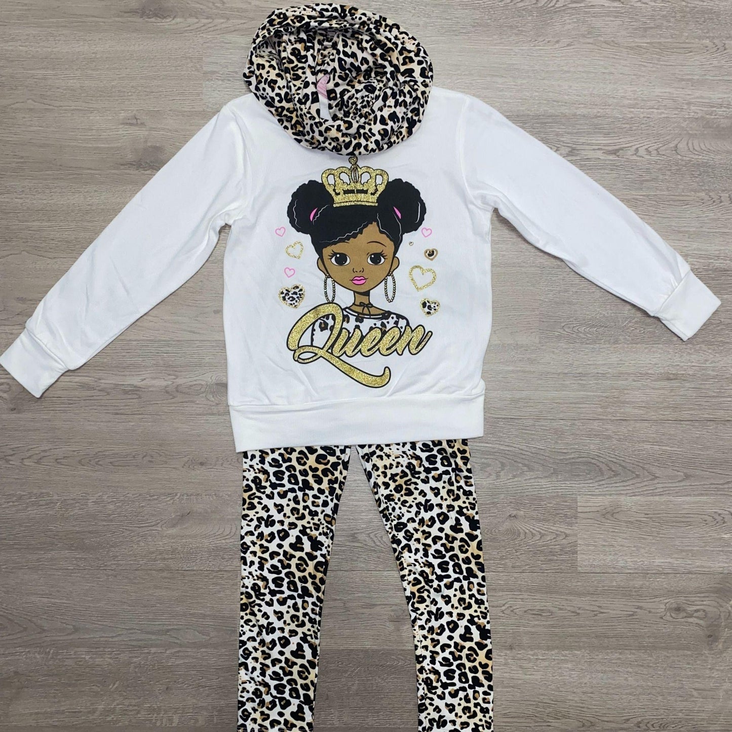 Get ready for fall in this cozy legging set.  This set features an ivory colored top with a screen pressed "Queen" design and cheetah print leggings.  The top also has an attached cheetah print scarf to complete the outfit.