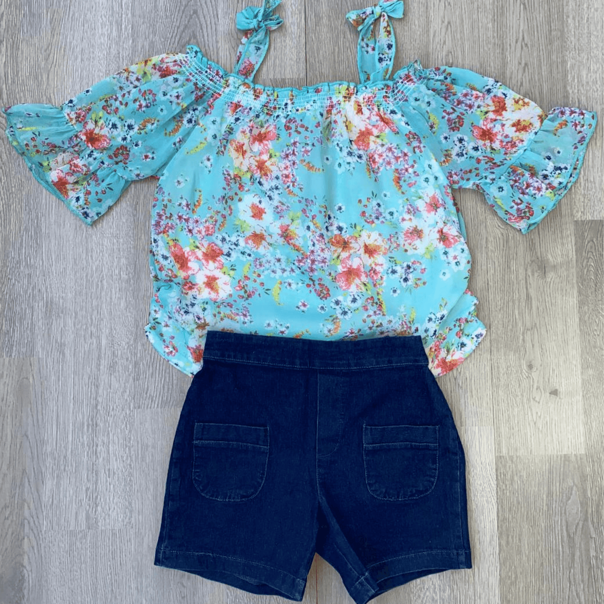 Be summer ready with this cute 2 piece short set featuring an off the shoulder, light weight blouse.  The blouse is mint colored with tie up straps and a floral print.  The shorts are denim colored with an elastic waist and two front pockets.